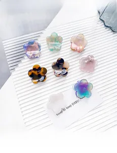 Detailed set of eight colorful floral acetate hair claws in various finishes on a glass tray