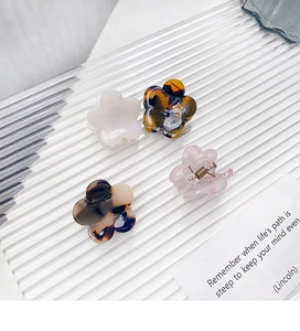 Detail showing four mini flower hair claws in pearl white, pink, and tortoiseshell acetate