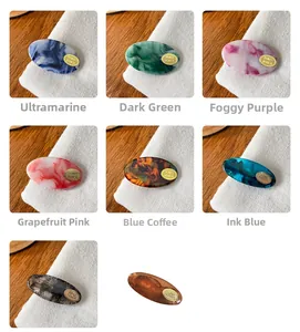 Detail view of acetate hair clips in eight colors with marble textures and gold logo