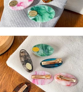 Detailed macro view of POKO FOSCA marble textured hair clips with gold metal base