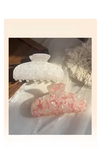 Detail of French vintage marble acetate hair claws with pearls on elegant silk background