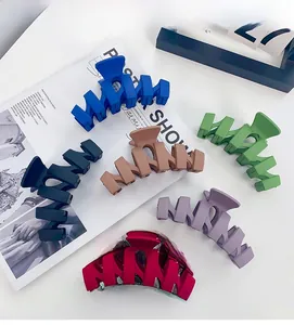 Detailed view of six matte wavy hair claws in blue, black, and more on a white desk