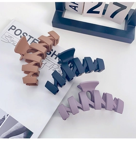 Close-up of three matte 13cm oversized hair claws in brown, navy and purple colors