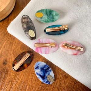 7-piece set of acetate oval hair clips with marble texture on rustic linen and wood