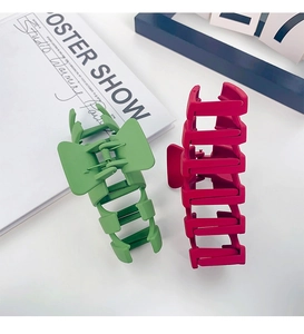 Close-up of red and green 13cm matte shark hair clips with a minimalist hollow design