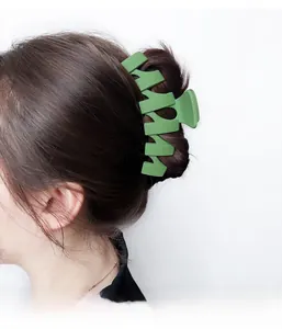 Macro detail of avocado green matte hair claw clip worn on model with thick hair