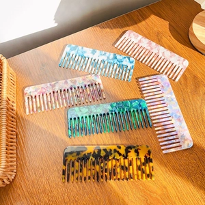 Elegant tortoiseshell acetate hair combs in various colors on a wooden table in sunlight