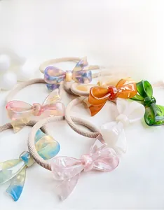 Detail of colorful acetate bow hair ties showing high-elastic bands and glossy texture