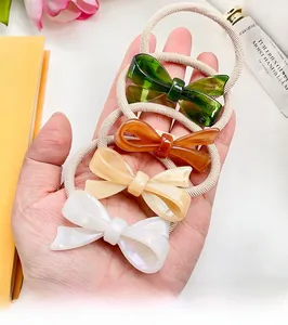 Detailed macro of four acetate resin bow hair ties in green, amber, beige and white colors