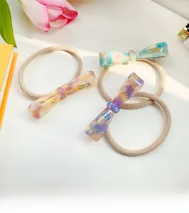 Détail des chouchous nœuds en acétate faits main avec inscription dorée sur bande élastique