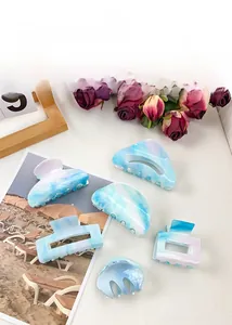 Detail view of five sky blue marble pattern acrylic hair claws in various geometric shapes