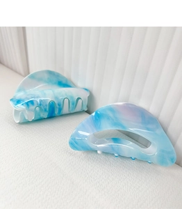 Detail of light blue marble pattern acetate hair claws on a textured background