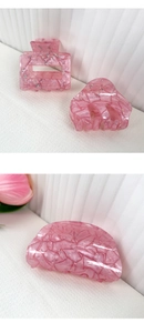 Détail de pinces à cheveux en acrylique rose pailleté avec découpes et texture marbrée
