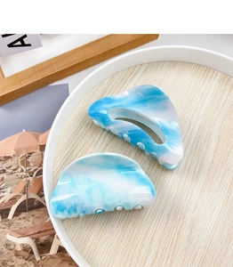 Detailed view of blue and white marble acrylic hair claws on a decorative wooden tray