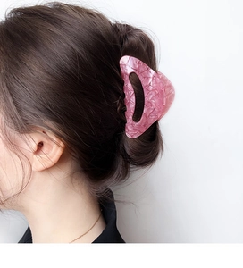 Détail d'une pince à cheveux en acrylique rose marbré portée sur une coiffure élégante