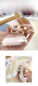 Detail of large acrylic hair claws with marble texture and durable metal springs