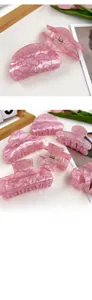 Détail macro de pinces à cheveux roses pailletées avec ressort doré et motifs floraux