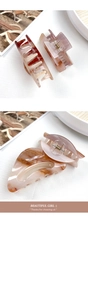 Close-up of marble texture acrylic hair claws with gold springs in soft warm tones