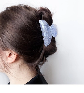 Close-up of a large blue and purple marbled acetate hair claw clip on brunette hair