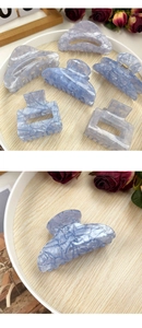 Detailed close-up of light blue marble textured acetate hair claws with metallic springs