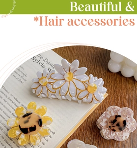 Floral hair claws with daisy and sunflower designs displayed on a rustic wooden table