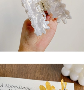 Macro detail of marble white and amber floral claw clips with glossy resin finish