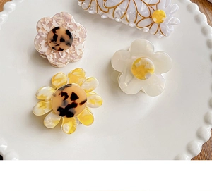 Close-up of floral acetate hair claws with marble pink and pearlescent white textures