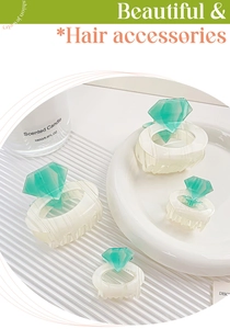 Detail of cream acetate hair claws with mint green rhinestone accents in a set