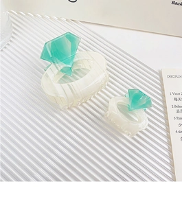 Detail view of two cream acetate hair claws with mint green diamond-shaped accents