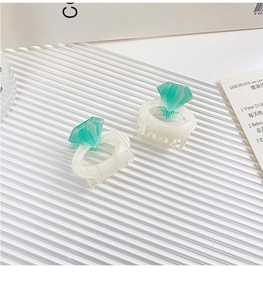 Close-up of two mini cream acetate hair claws with mint green diamond-shaped accents