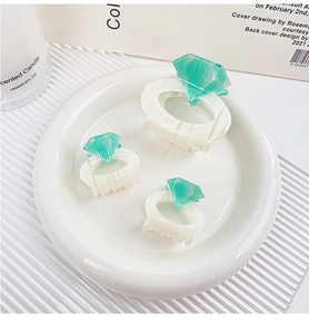 Detailed set of pearl white and mint green diamond-shaped hair claws on ceramic tray