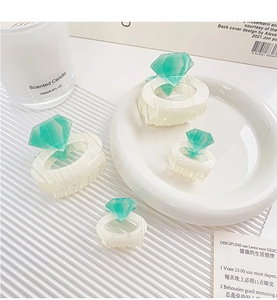 Detail view of cream marble hair claws with green diamond accents in a luxury setup