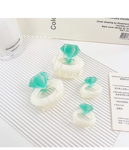 Detail view of four-piece cream hair claw set with green geometric diamond accents
