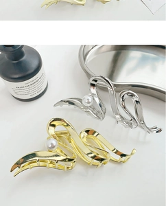 Dettaglio di fermagli per capelli in metallo a onde oro e argento con eleganti perle grandi