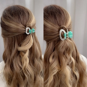 Elegant green hair claw clip with oval rings shown on wavy hair from side and back views