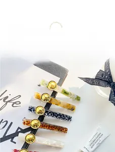 Detail of acetate hair clips with leopard print, marble texture and golden buttons
