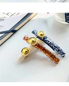 French vintage acetate hair clips with leopard print and gold button details in close-up