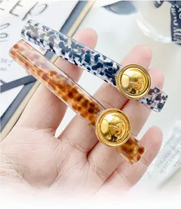 Detail of tortoise shell and black-white acetate hair clips with golden metal buttons