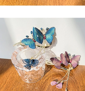 Detail view of embroidered butterfly hair clips with long metal tassels and crystal accents