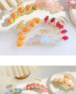 Detailed macro shot of diverse acrylic hair claws with fruit and floral patterns