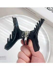 Gros plan d'une pince à cheveux noire brillante montrant le ressort doré et le design