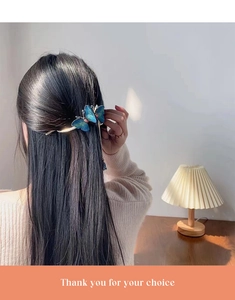 Close-up of blue embroidered butterfly hair clip with tassels on a female model