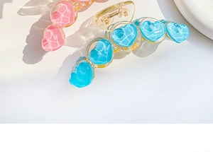 Detail of pink and blue acrylic heart hair claws with marble texture and metal spring