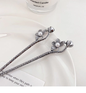 Détail des épingles à cheveux en métal gris avec perles fleurs de prunier sur assiette