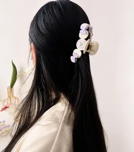Close-up of cream-colored hair claw with purple bow detail worn on black hair