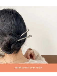 Gros plan d'un pic à cheveux en métal argenté au design fluide dans un chignon