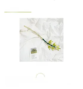 Detailed close-up of golden bamboo leaf hair pin with green enamel and elegant texture