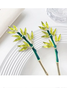 Detail of bamboo leaf hair stick with green enamel finish and gold metal edges