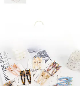 Detailed view of cat-shaped acetate hair clips in colorful marble and floral patterns