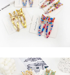 Cat-shaped acetate hair clips with marble patterns and gold accents on a jewelry card